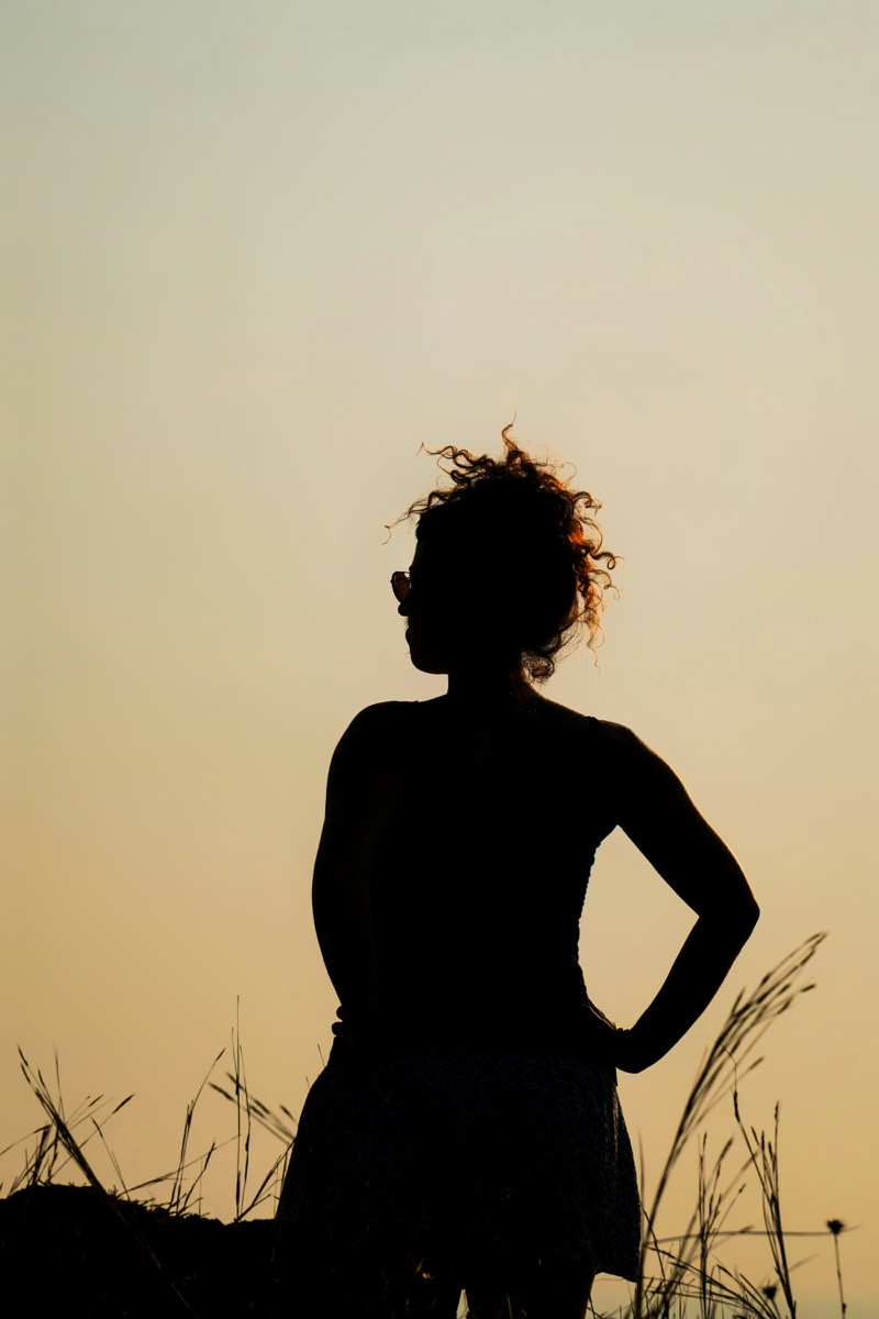 Woman standing confidently on a hilltop at golden hour