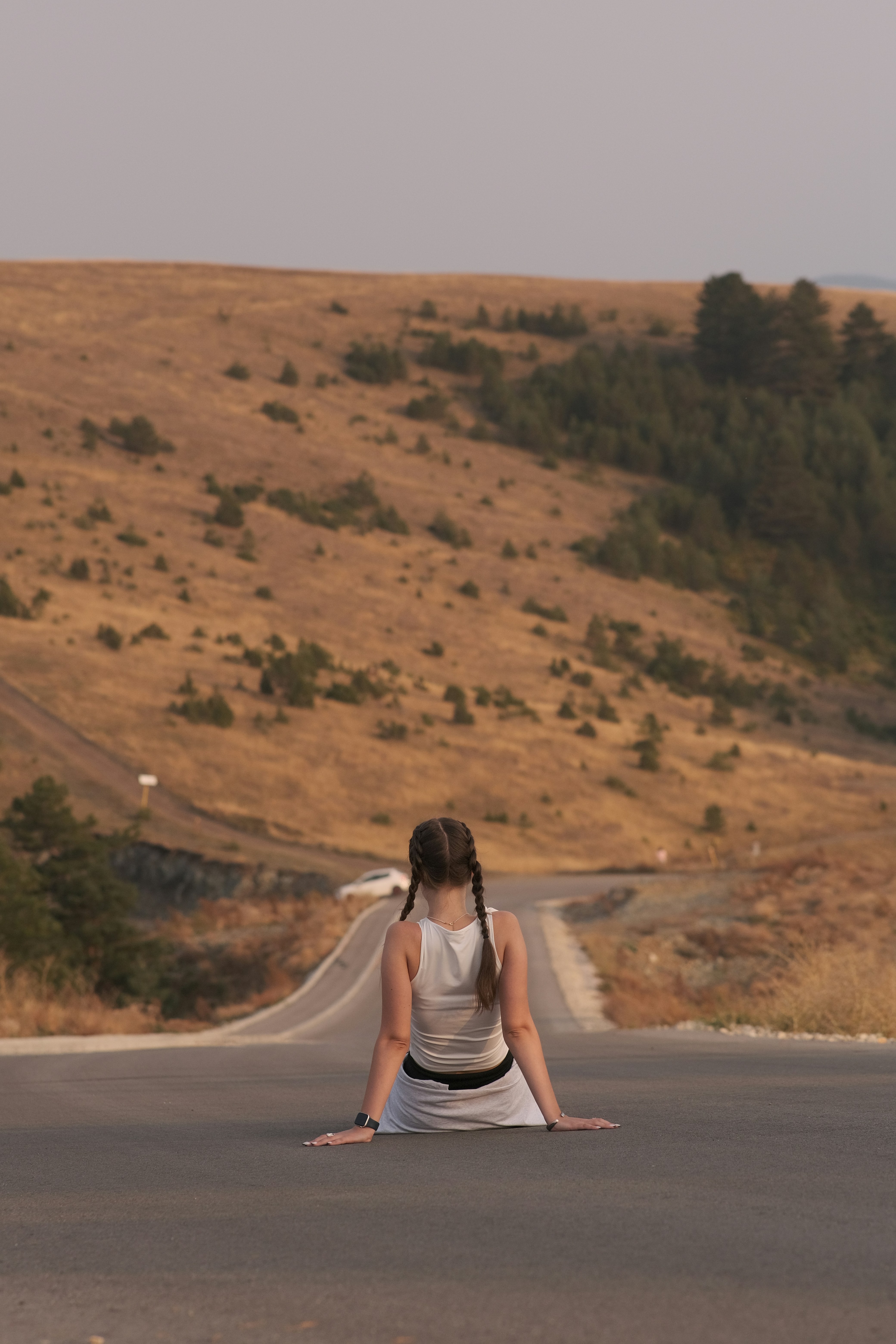 Woman sitting on a road looking toward a hill ahead, contemplating her path